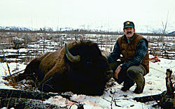 A hunter kneeling next to a bison he brought down