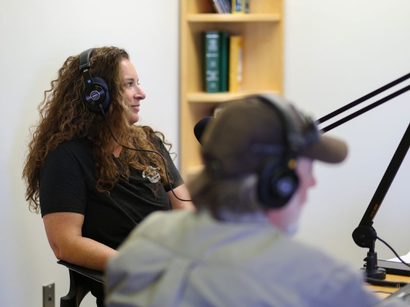 Brittany speaking into a microphone with headphones on
