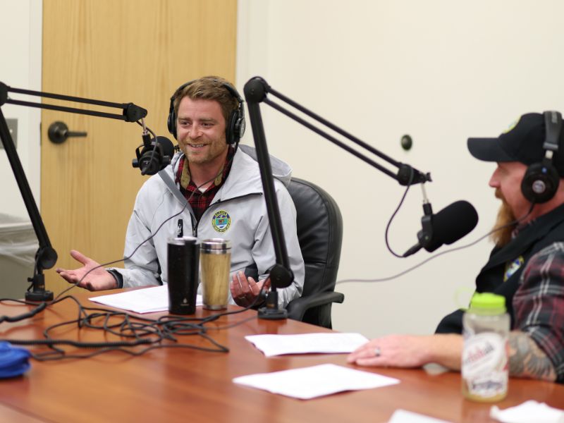 Oliver speaking into a microphone with headphones on smiling