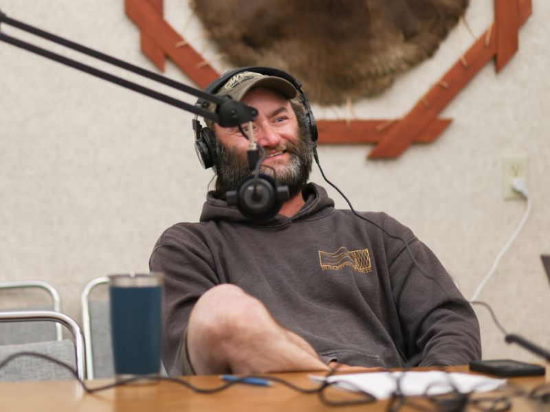 Matt speaking into a microphone with headphones on smiling