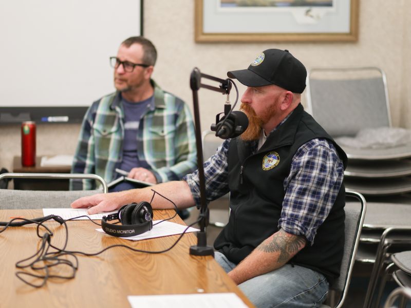 Ryan interviewing Matt in a microphone with headphones on