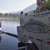 College Intern, Mike Komparda, holds the stocking hose in preparation for rainbow trout fingerling to be released into Summit Lake.