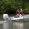 Technicians spool a beach seine net from the back of a boat.