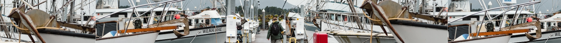 A man walking between fishing boats